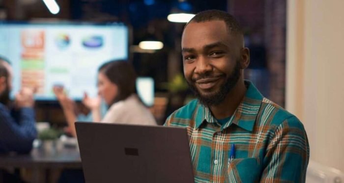 Smiling african american office employee working on laptop portrait